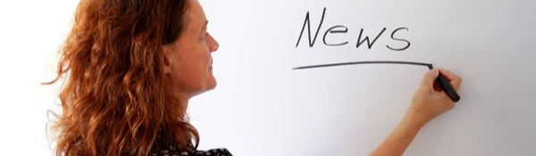 Eine Frau schreibt mit einem Filzstift „Nachrichten“ auf eine weiße Tafel.