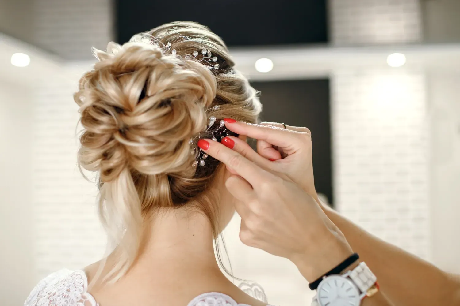 Persona que se está peinando, con un recogido complejo, en un salón.