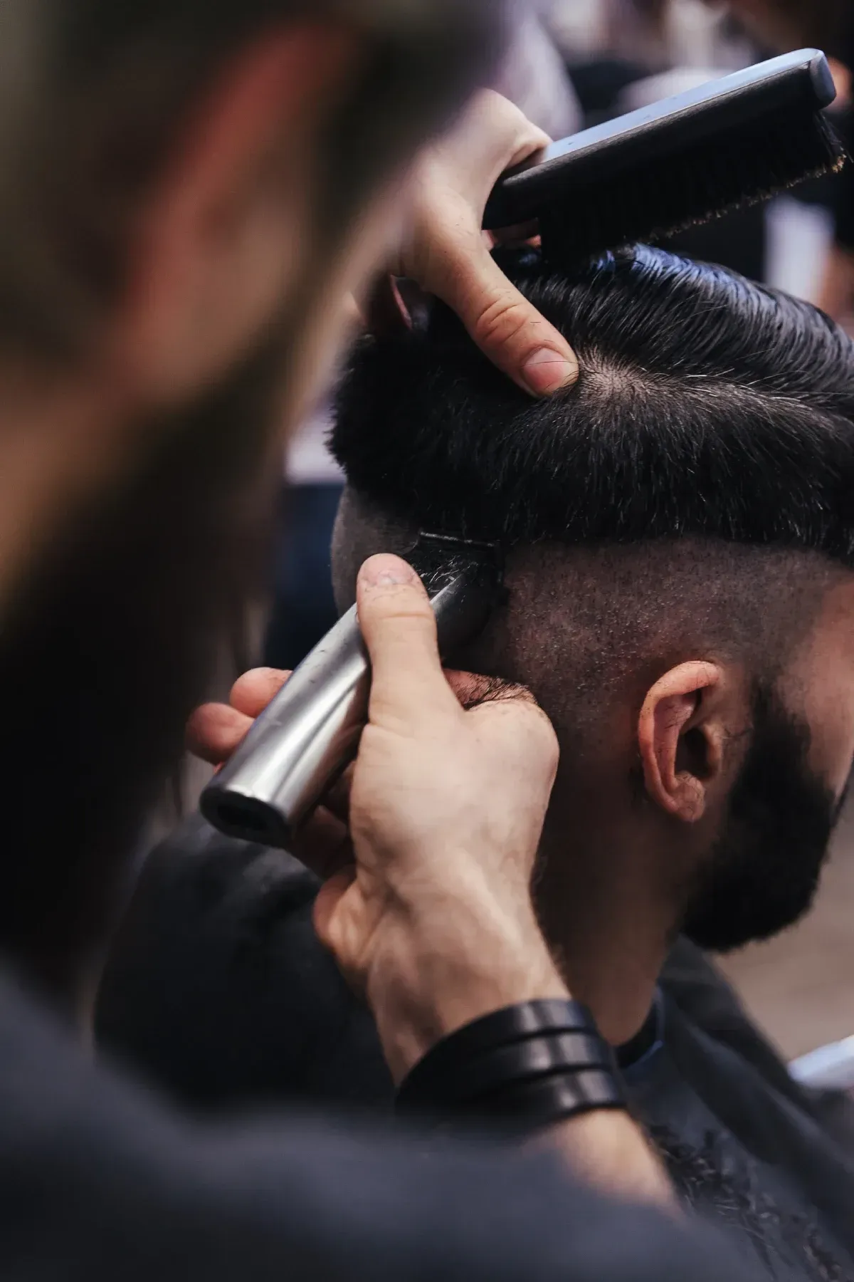 Un barbero corta el pelo a una clienta con una maquinilla. Primer plano del corte en el salón.