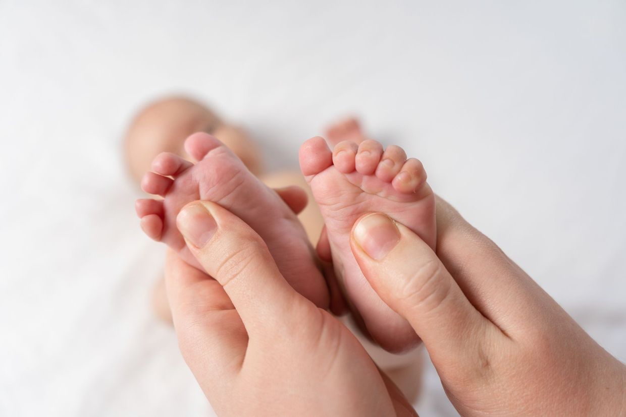 Une femme tient les pieds d'un nouveau-né.