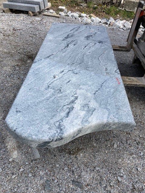 Grande dalle en pierre grise avec bordure naturelle, extérieur sur gravier.