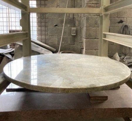 Un grand comptoir circulaire en granit poli repose sur une table dans un atelier.