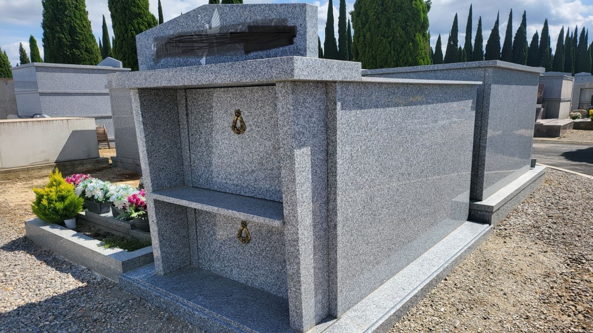 Tombeau en granit gris dans un cimetière.