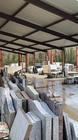 Un espace extérieur couvert avec des piles de dalles de pierre et des machines.