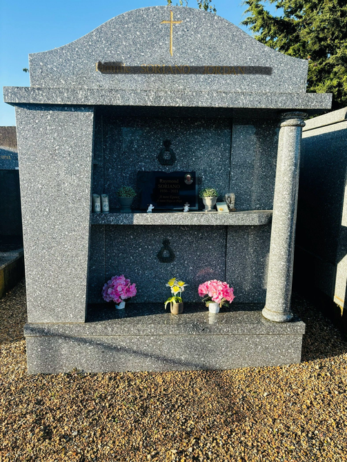 Mausolée en pierre avec des fleurs dans un cimetière.