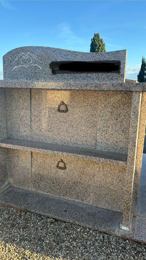 Tombeau en pierre à deux niveaux, chacun doté d'un anneau métallique. L'arrière-plan présente une ouverture sombre.