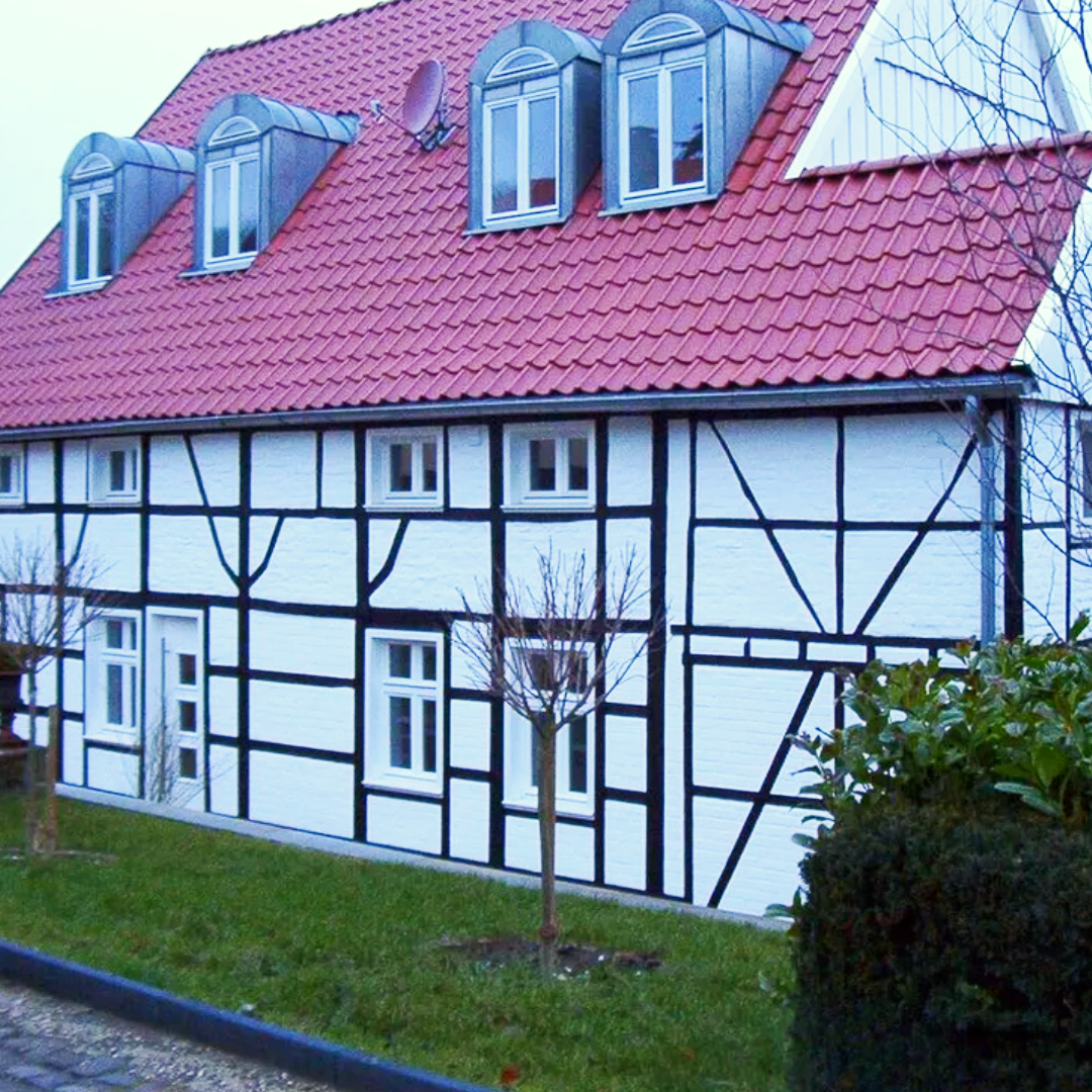 Ein weiß-schwarzes Haus mit einem roten Dach
