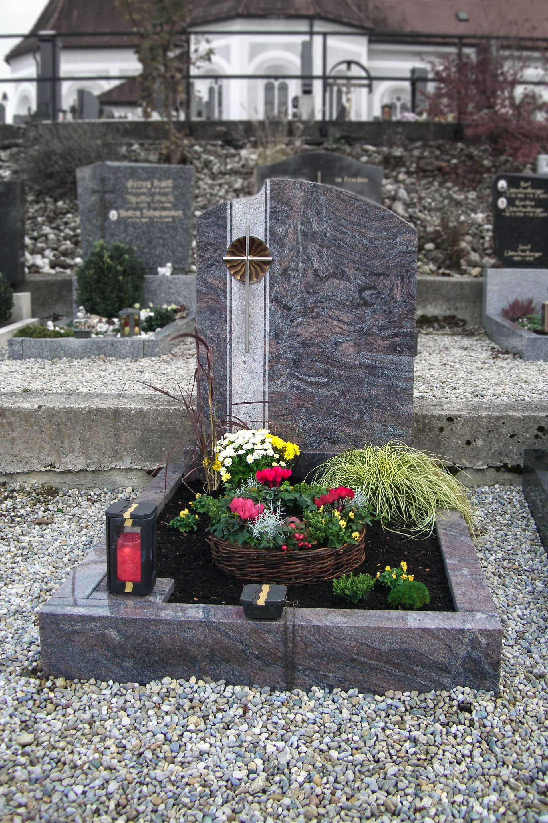 ein Grabstein mit Blumen und einer Laterne darauf