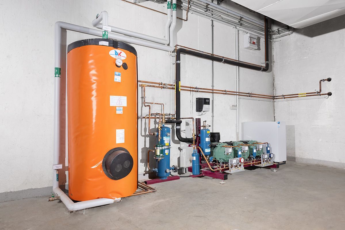 Orangefarbener Warmwasserbereiter mit Rohren und anderen mechanischen Geräten in einem Raum.