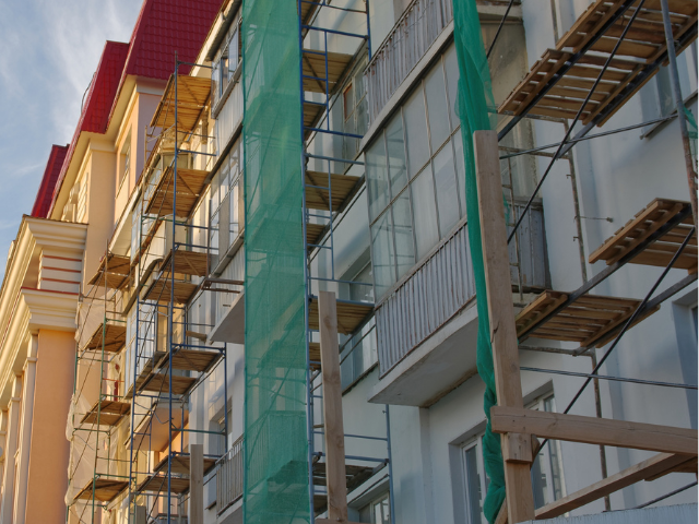 Extérieur du bâtiment avec échafaudage et filet de protection pendant la construction.