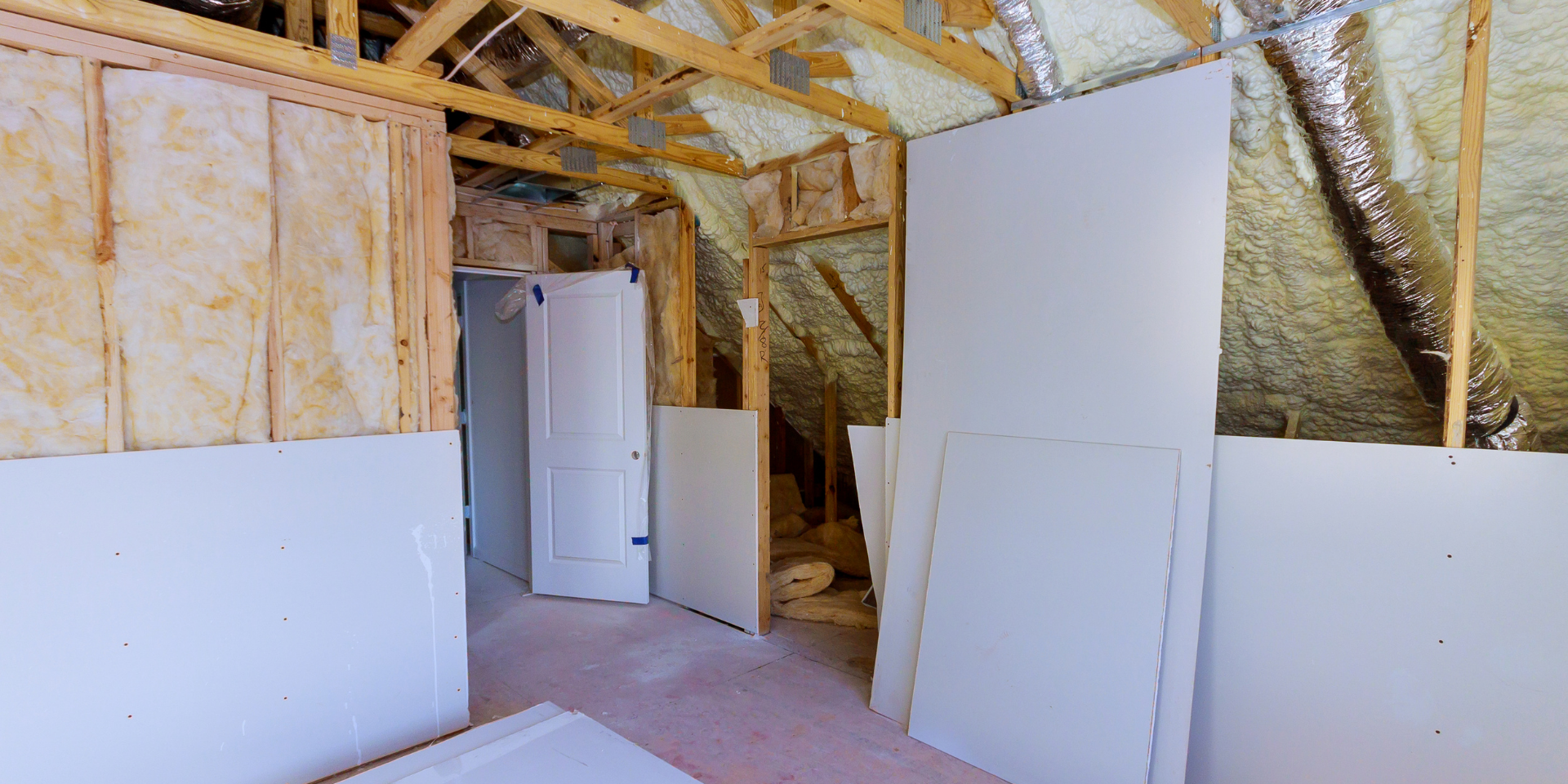 Vue intérieure d'une pièce inachevée avec cloisons sèches et isolation apparente.