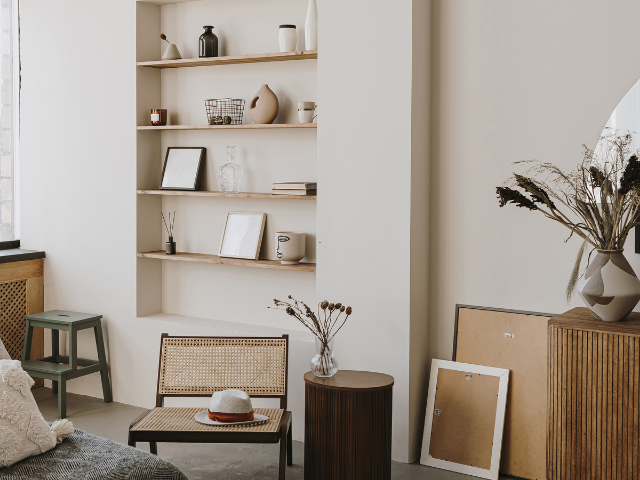 Salon aux tons neutres avec étagères intégrées, chaise tissée et décoration.
