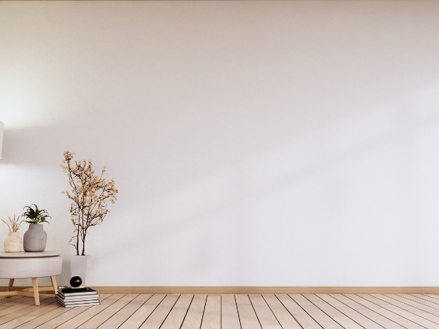 Mur blanc avec plancher en bois, table d'appoint avec vases et plantes.