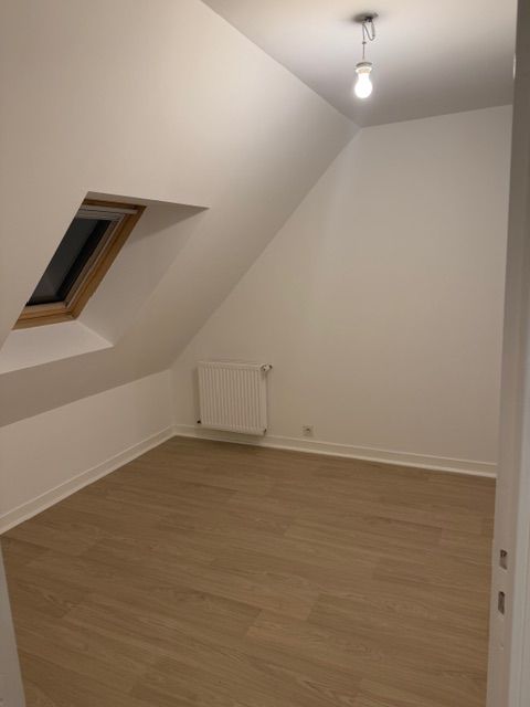 Personne installant du parquet, appliquant de la colle près d'un mur blanc.