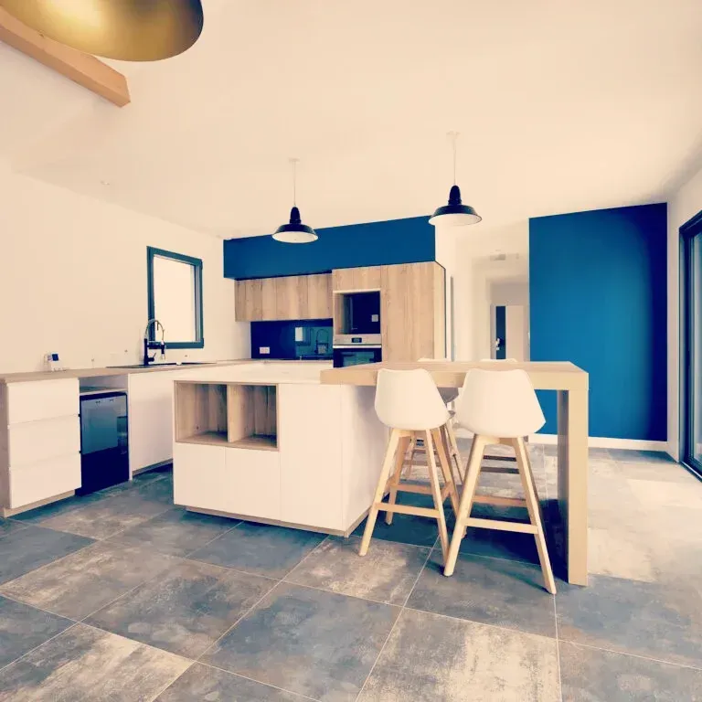 Cuisine moderne avec îlot, tabourets et murs d'accent bleu.