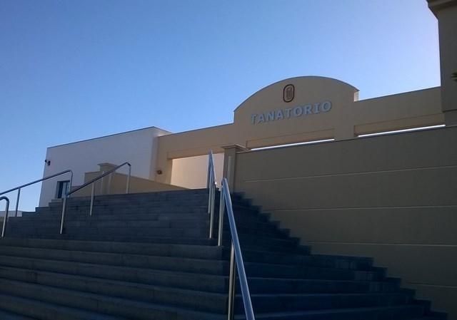Escalera que conduce a la entrada de un edificio beige con pasamanos bajo un cielo azul claro.