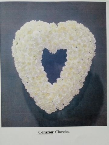 Arreglo floral blanco en forma de corazón sobre un fondo oscuro, con el centro hueco.