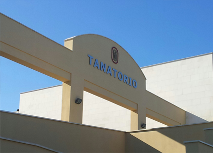 Letrero de entrada al Tanatorio en un edificio color crema bajo un cielo azul claro.