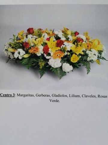 Centro de mesa floral colorido con margaritas, rosas, lirios, gladiolos y claveles sobre follaje verde.