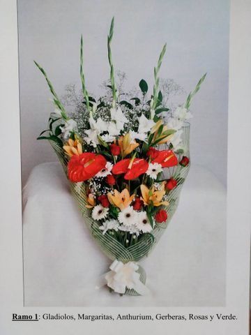 Ramo envuelto en celofán transparente con flores rojas, blancas y naranjas con follaje verde.