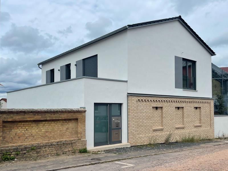 Ein weißes Gebäude mit einer Backsteinmauer und einem Dach