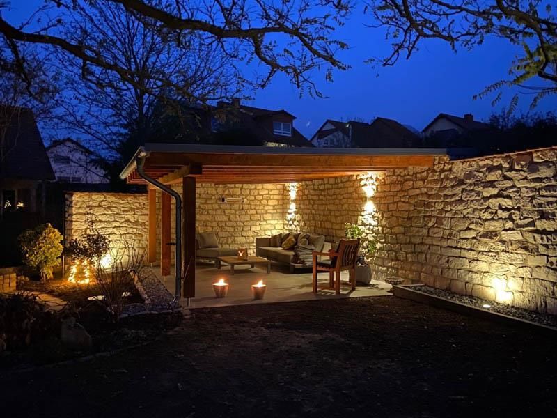 Eine Terrasse mit Sofa und Stühlen und Kerzen, die nachts beleuchtet werden