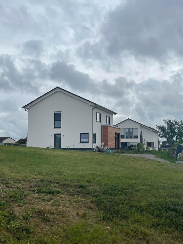 Auf einem grasbewachsenen Hügel steht ein weißes Haus.