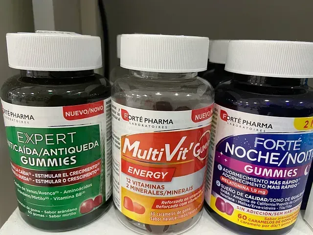 Hay tres botellas de gomitas multivitamínicas en un estante.