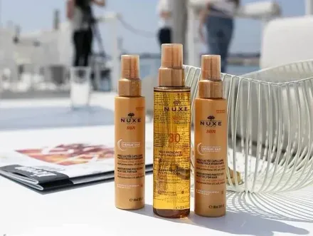 Hay tres botellas de productos capilares Nuxe sobre una mesa.