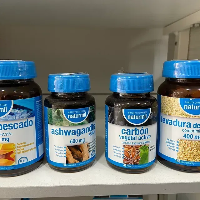 Cuatro botellas de productos naturales están alineadas en un estante.