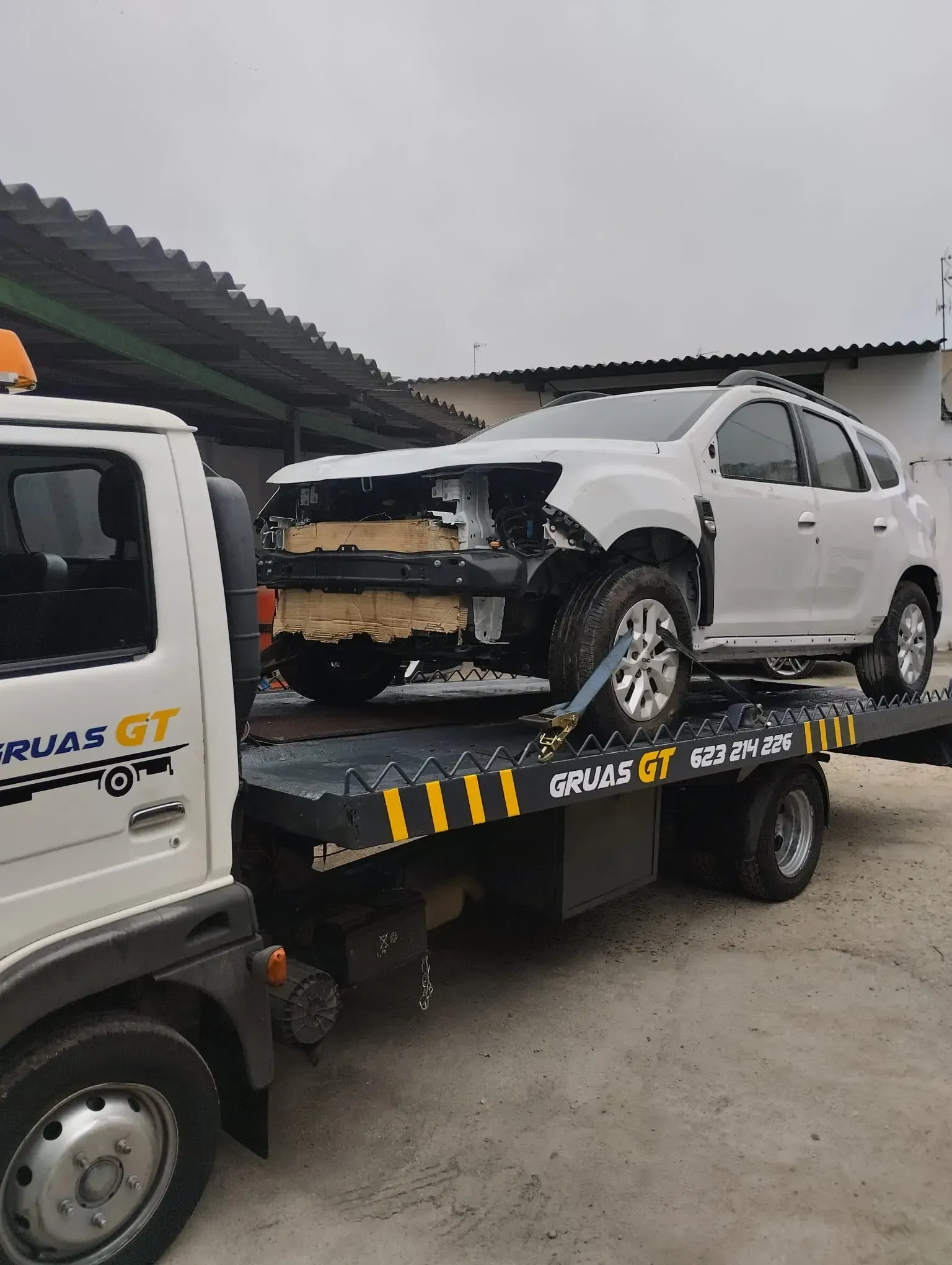 SUV blanco con daños en la parte delantera cargado en una grúa.