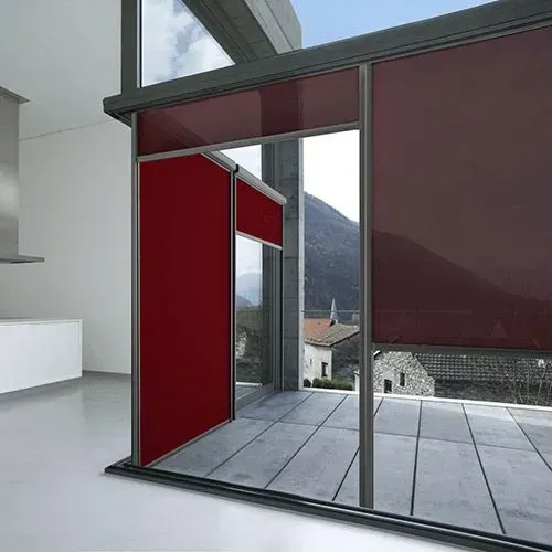 Habitación moderna con grandes paneles corredizos rojos y ventanales de suelo a techo con vistas a la montaña.