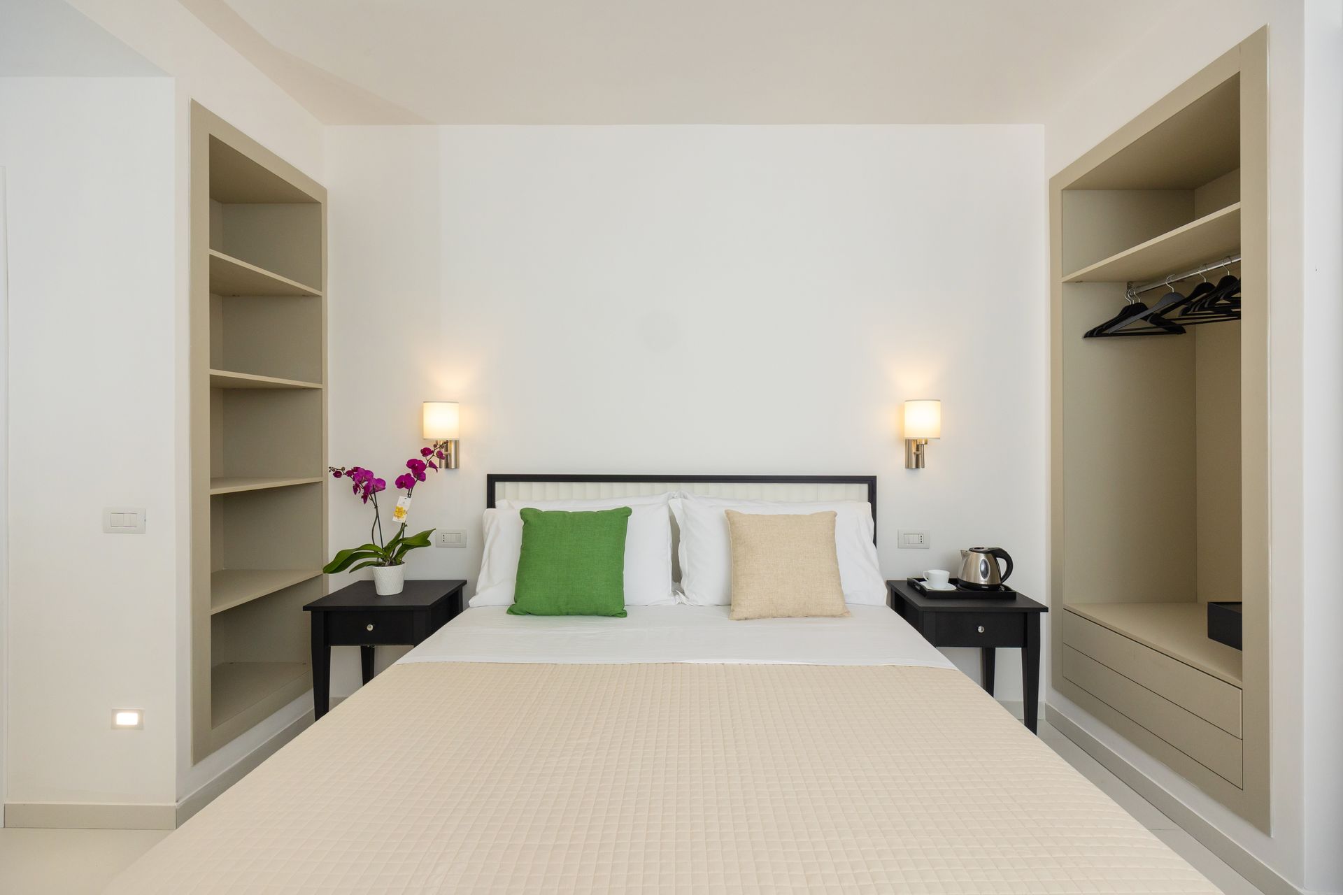 Bedroom with a bed, nightstands, built-in shelves, and neutral colors.