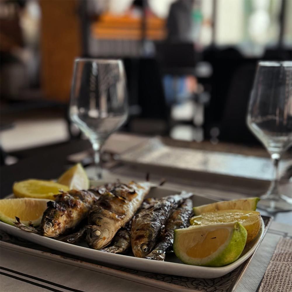 Un plato de comida con rodajas de limón y copas de vino sobre una mesa.