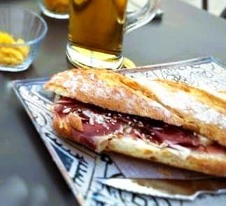 Dos tazas de café y un sándwich en un plato sobre una mesa.
