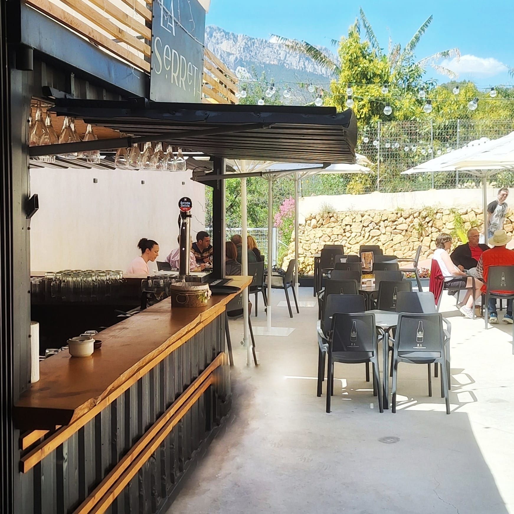 Un grupo de personas están sentadas en mesas afuera de un restaurante.