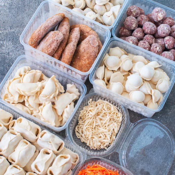Una variedad de alimentos congelados en recipientes de plástico sobre una mesa.