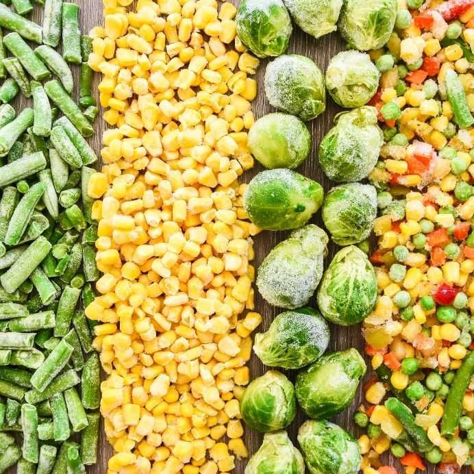 Hay muchos tipos diferentes de verduras congeladas en una mesa de madera.