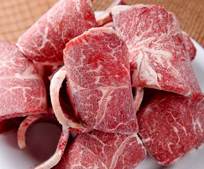 Un plato blanco cubierto con trozos de carne cruda.