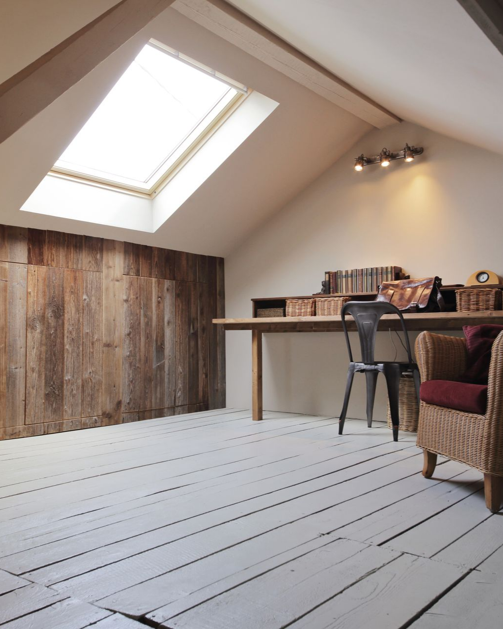Bureau mansardé avecune fenêtre de toit qui illumine la pièce.