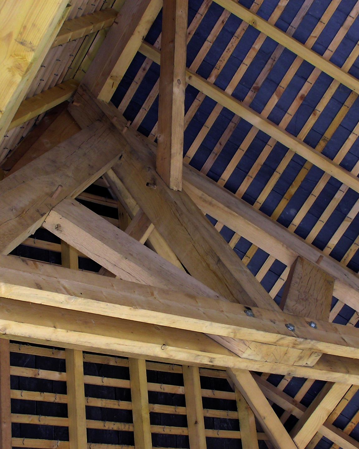 Charpente de toit en bois avec chevrons et matériau isolant.