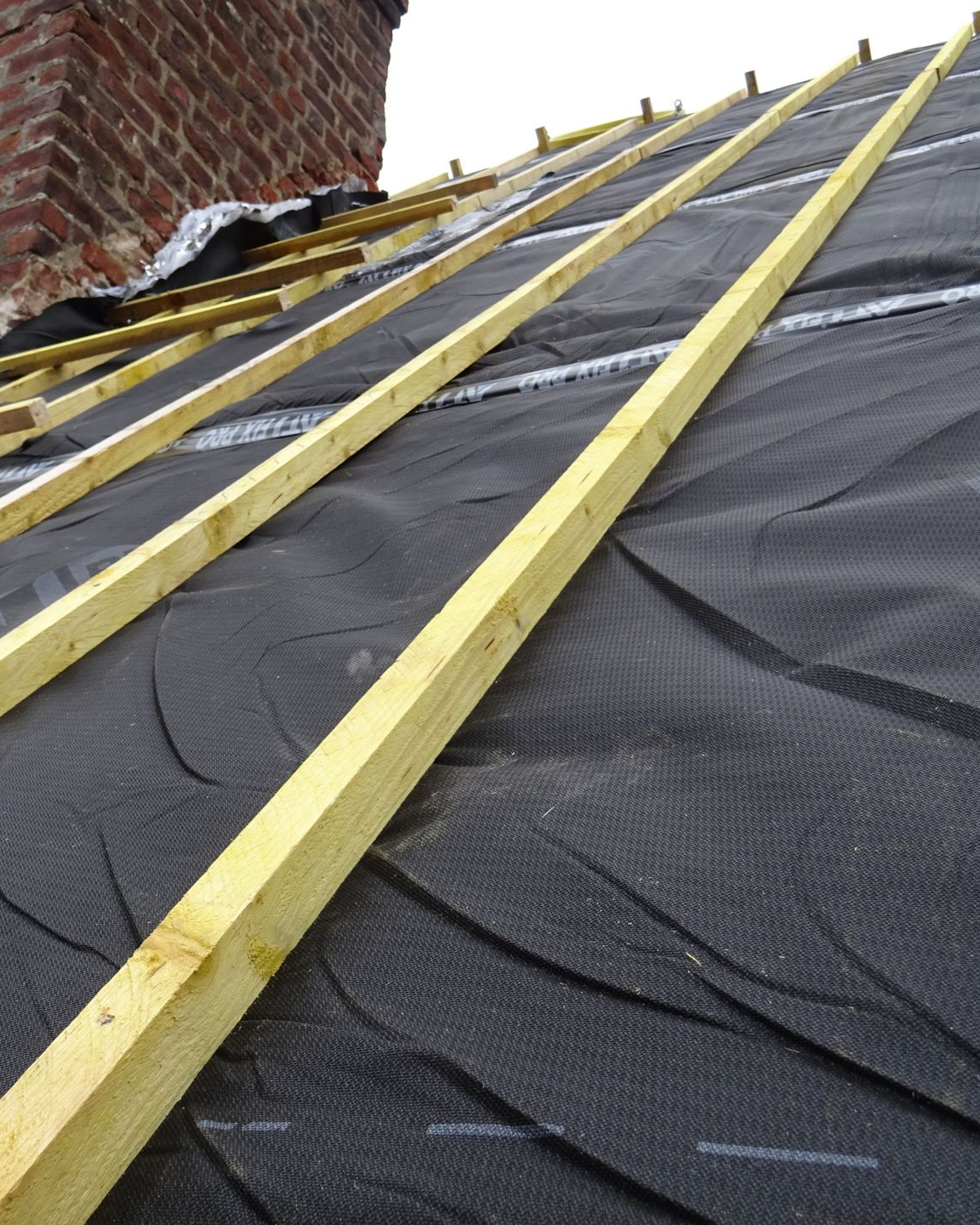 Toiture en construction avec un isolant mince et des chevrons en bois.