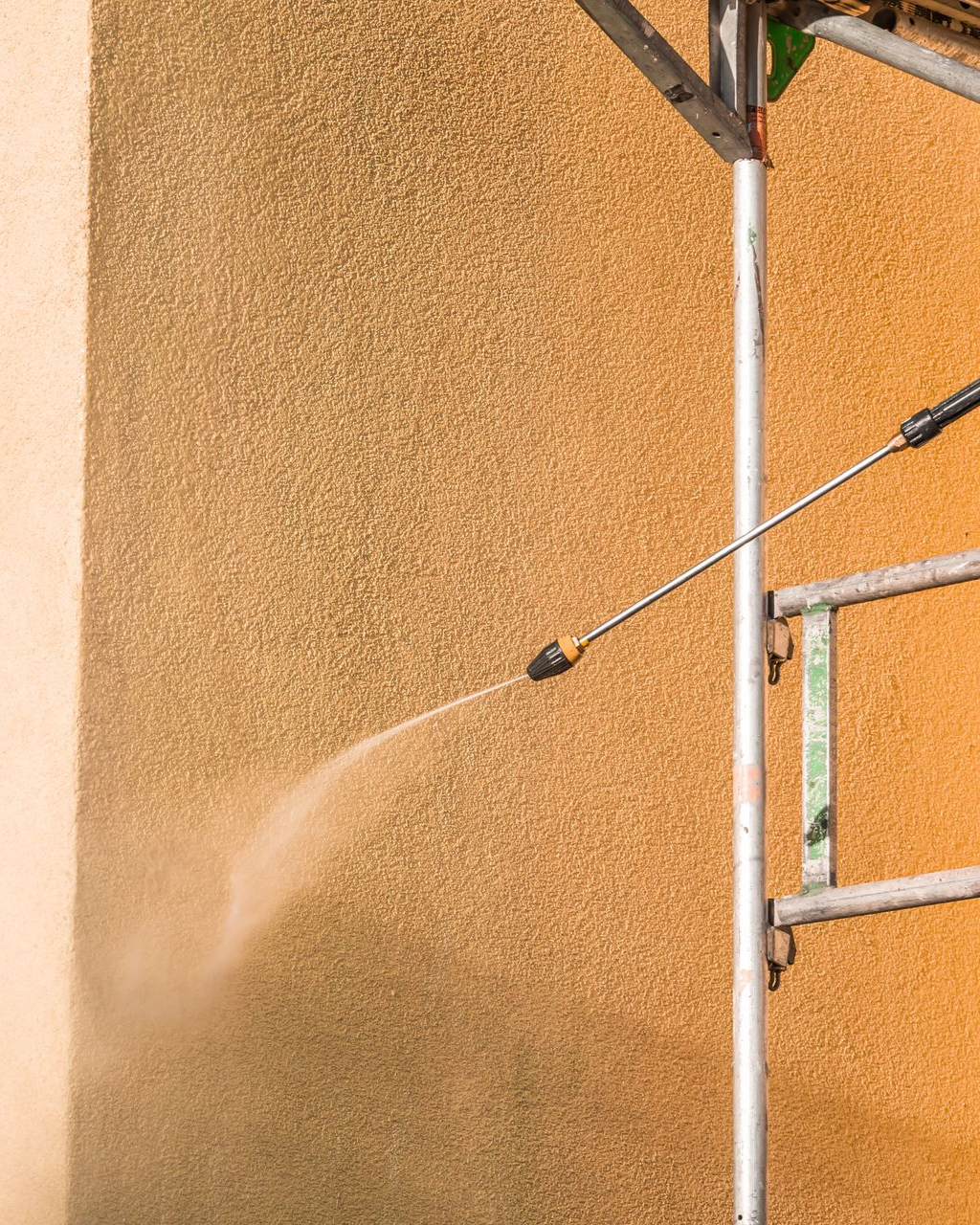 Une personne nettoie une façade à haute pression.