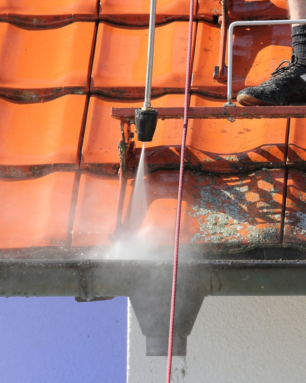 Une personne nettoie un toit en appliquant un hydrofuge.