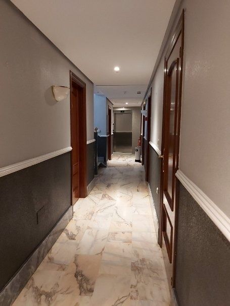 Un largo pasillo con suelos de mármol y paredes grises.