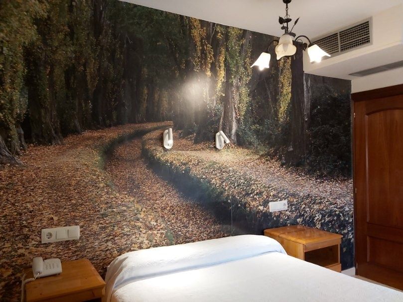 Un dormitorio con una imagen de un bosque en la pared.