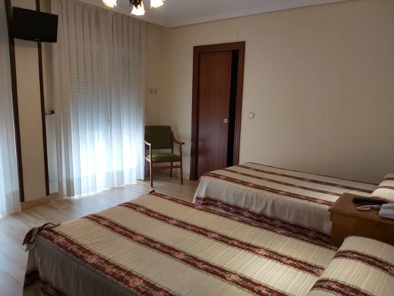 Una habitación de hotel con dos camas, una silla y un televisor.