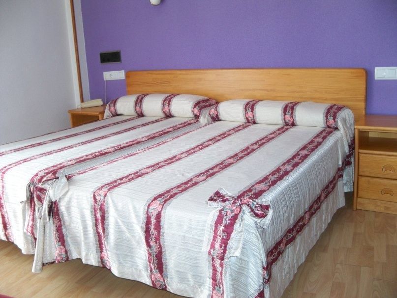 Un dormitorio con dos camas y una pared morada.