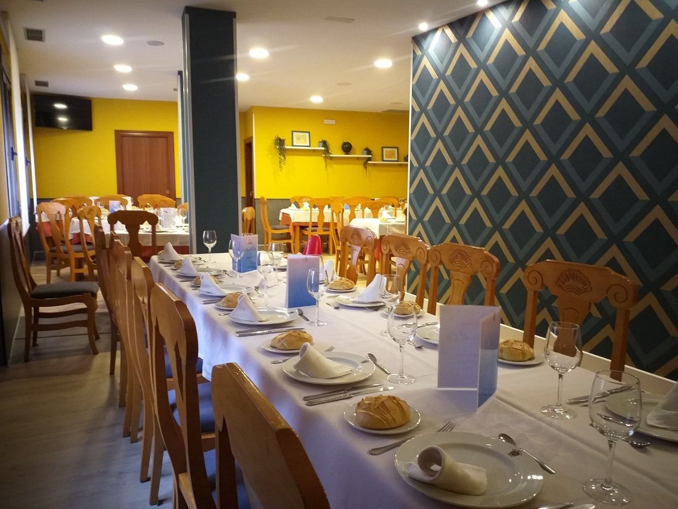 Una mesa larga en un restaurante con platos y vasos encima.