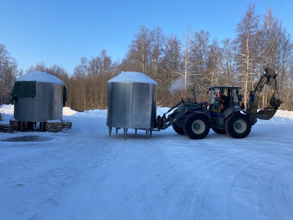 Traktori talvisessa maisemassa ulkona kuljettamassa säiliötä.